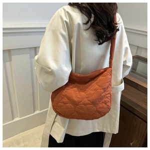 Detail of orange heart-quilted crossbody bag with matching shoulder strap on a model