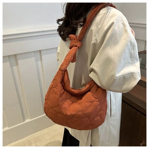 Détail du motif matelassé en cœur et de la large bandoulière nouée du sac orange