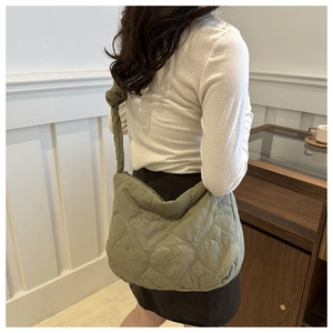 Detail of avocado green quilted shoulder bag with heart patterns and soft fabric texture