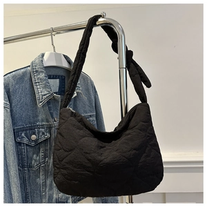 Détail du sac cabas noir matelassé en cœurs avec bandoulière à nœud décoratif élégant
