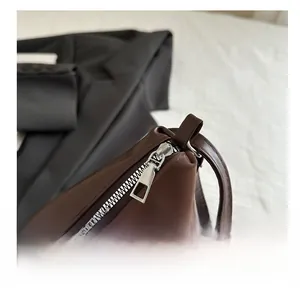Detail of smooth silver metal zipper and precise stitching on dark brown leather bag