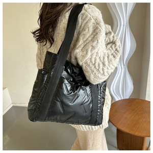 Detail einer schwarzen gesteppten Puffer-Einkaufstasche mit Glanzeffekt im Lifestyle-Stil