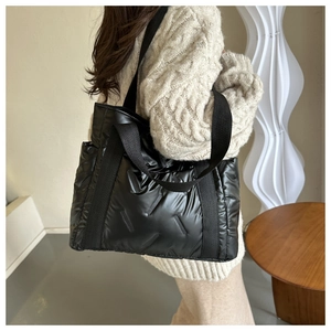 Detail einer schwarzen gesteppten Daunen-Tote-Bag aus glänzendem wasserfestem Nylon