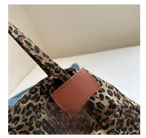 Macro detail of leopard print tote featuring leather patch and metal rivet hardware