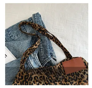 Detail of leopard print tote bag with brown leather patch on textured fabric