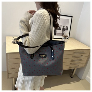 Detail of grey canvas tote with red polka dots and black leather shoulder straps