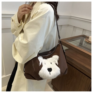 Detail of brown nylon shoulder bag featuring a plush Schnauzer dog patch and silver zipper