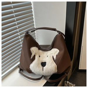 Detail of dark brown tote bag featuring a plush white puppy patch and glossy finish