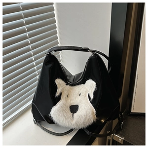 Detail of a black hobo bag featuring a white plush Schnauzer dog motif and slim shoulder strap