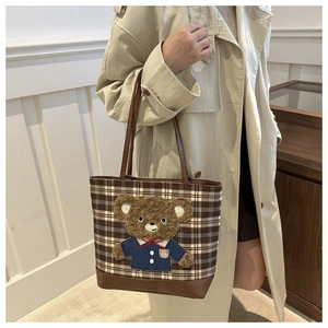 Detail of a brown plaid tote bag with 3D teddy bear patch on an autumn canvas fabric