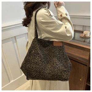 Close-up of leopard print canvas tote bag with front V-shaped pocket and leather label