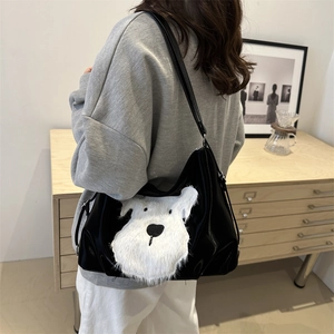 Minimalist black faux leather tote bag with a white plush dog patch and wide shoulder strap
