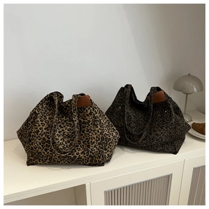 Large leopard print tote bags in canvas and leather on a minimalist white cabinet