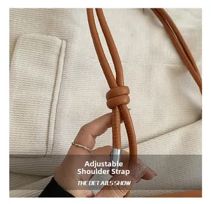 Detail of adjustable tan lychee leather strap with silver buckle for shoulder bag