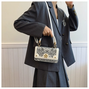 Detail van vintage vierkante tas met zwart-wit geweven patroon en gouden bloemsluiting
