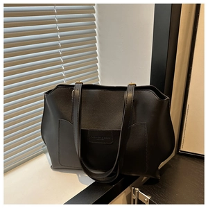 Dettaglio della borsa tote in pelle PU nera con toppa logo a rilievo e manici robusti