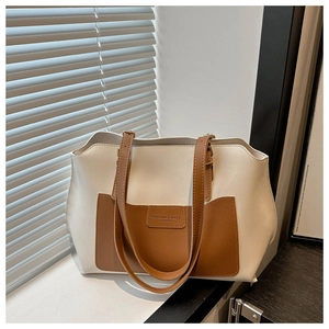 Dettaglio della borsa tote crema con tasca marrone a contrasto e logo in pelle goffrata