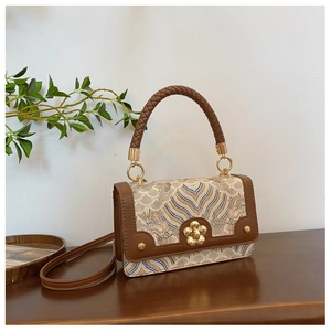 Detail of vintage brocade handbag with embroidery patterns and leather woven handle