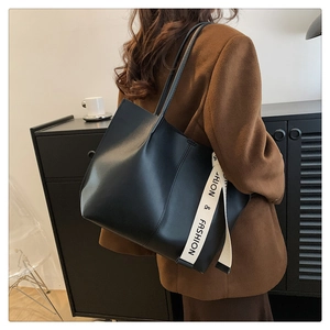 Detail of black faux leather tote bag with unique lettered canvas strap decoration