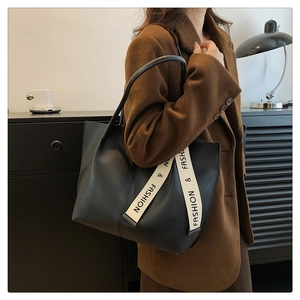 Detail van een grote zwarte leren shopper met een modieuze contrasterende riem op de schouder