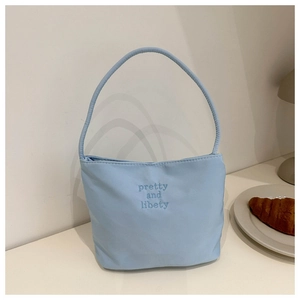 Détail du sac seau bleu clair avec broderie pretty and libety dans un décor minimaliste