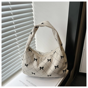 Détail du sac à main en velours côtelé blanc cassé avec motifs nœuds et losanges noirs
