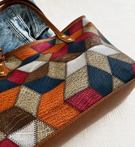 Dettaglio della borsa tote color-block con pelle martellata e rivetti in metallo dorato