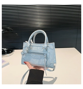 Close-up of light blue small square bag with pleated texture and tassel zipper detail