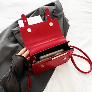 Detalle del bolso bandolera de cuero rojo mostrando espacio para móvil y tarjetas