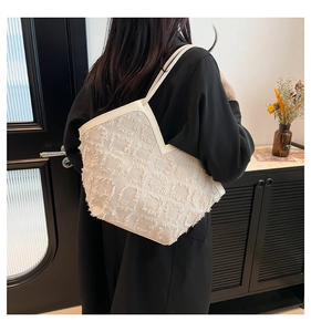 Détail d'un sac cabas beige avec textures carrées à franges et fines bandoulières
