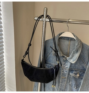 Detail der schwarzen Croissant-Tasche aus Wildleder mit Ziernähten und geknotetem Riemen