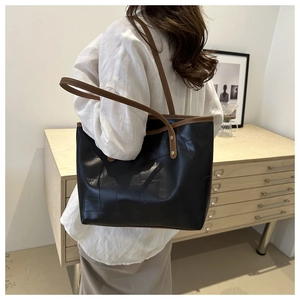 Dettaglio borsa shopper nera con finiture in pelle marrone e cuciture quadrate