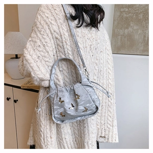 Macro shot of grey cloud bucket bag featuring textured fabric and gold butterfly accents