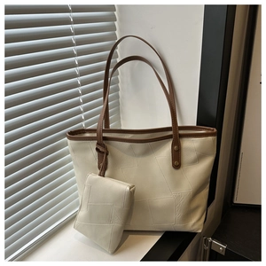 Dettaglio della borsa tote crema con cuciture geometriche e manici in pelle marrone