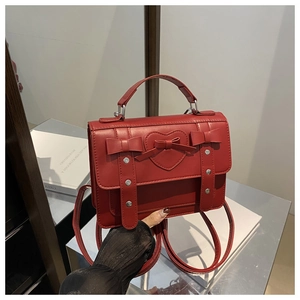 Detalle de una mochila de cuero rojo con relieve de corazón y lazos decorativos
