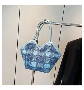 Detail of blue denim tote bag with frayed edges and unique V-shaped opening design