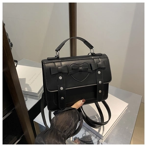 Detalle de bolso negro estilo JK Lolita con corazón de cuero y lazos decorativos
