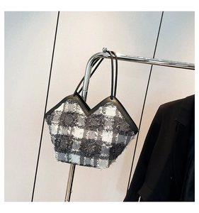 Detail of tweed checkered tote bag with fringe texture and black leather trim accents