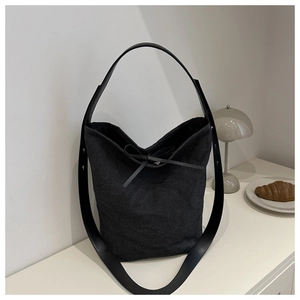 Détail du sac seau en toile gris foncé avec bandoulière en cuir et nœud décoratif