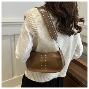 Detailansicht der braunen Vintage-Nietentasche, getragen von einem Modell im Casual-Look