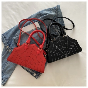 Detail of red and black crossbody bags with spider web stitching in a lifestyle setting