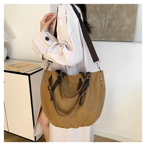 Detailweergave van de grote canvas tas met bruine riem en metalen klinknagelversterking