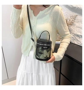 Detail of embroidered green butterfly on black bucket bag worn by model in casual style