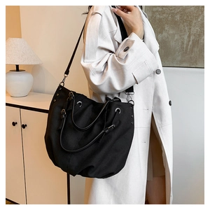 Borsa tote in tela nera con tracolla regolabile e dettagli in rivetti metallici