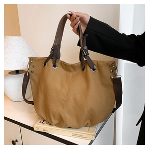 Dettaglio borsa tote in tela gialla con manici marroni e tracolla rimovibile