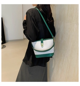 Detail of color-block bucket bag showing woven texture and gold clasp on a shoulder