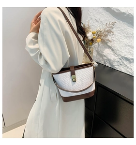 Detail view of woven texture crossbody bucket bag with brown trim and gold lock