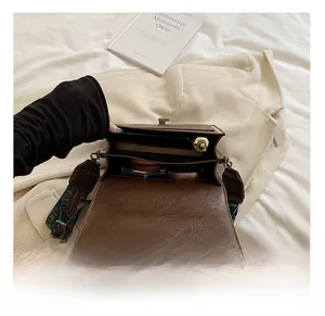 Detail of vintage brown crossbody bag with two compartments and wide embroidered strap
