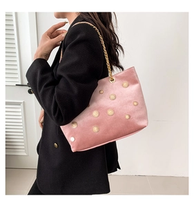 Detailed shot of pink velvet tote bag with gold sun buckles and fine chain strap on model