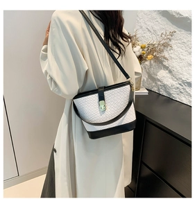 Detail of minimalist black and white bucket bag styled with a modern trench coat
